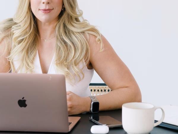 Close-up of Savannah Abney sitting at her laptop with a coffee mug, inviting founders to chat about which brand strategy service is right for their business growth.