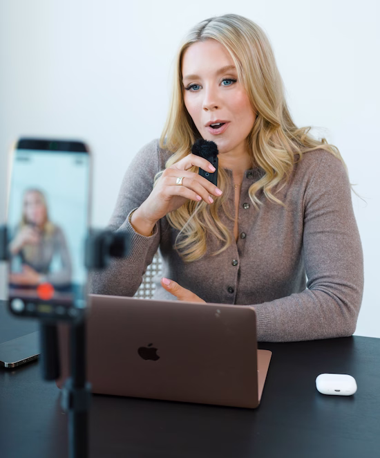 Savannah Abney speaking into a microphone at her desk, illustrating the high-touch, ongoing coaching she provides to help founders execute their brand strategy.